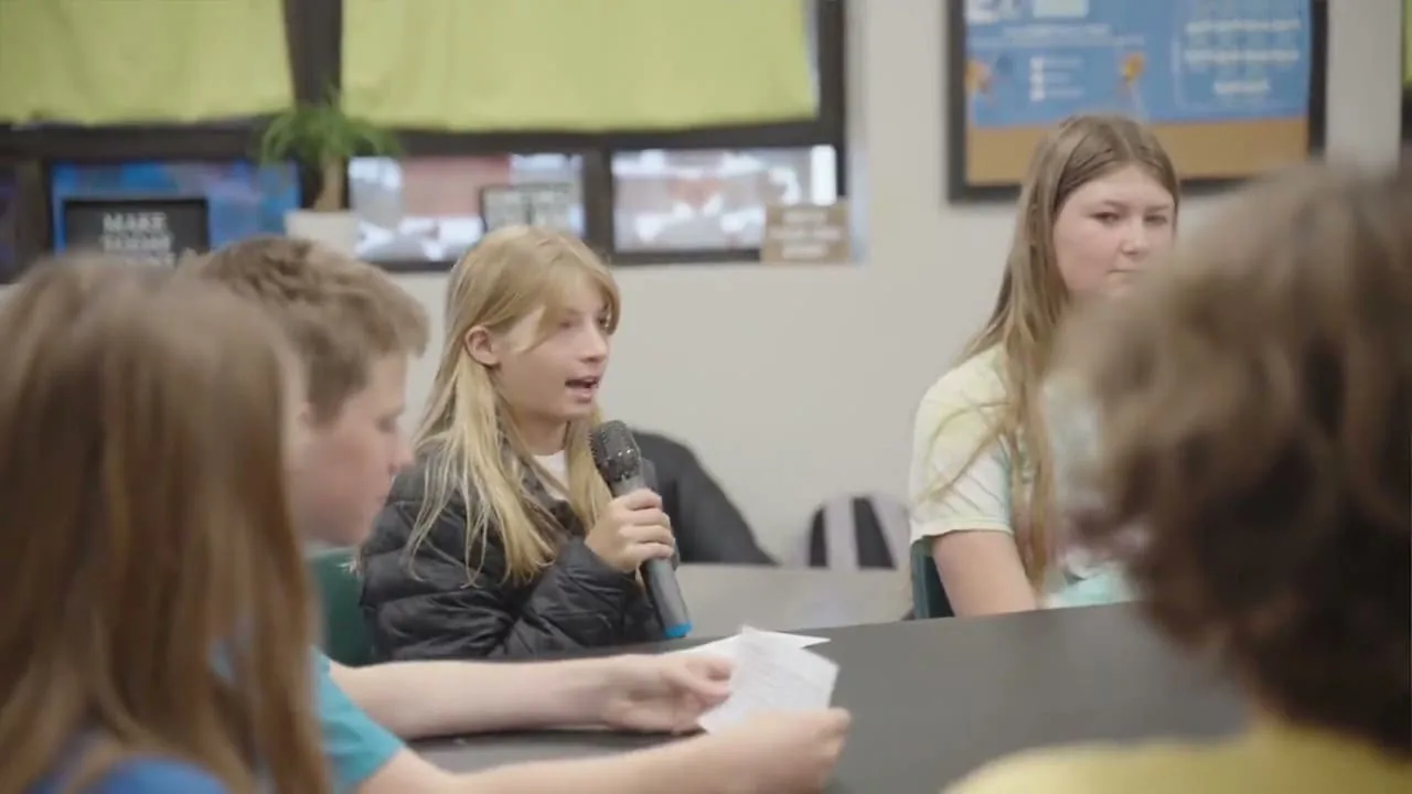 A student leading a SLED project discussion with the microphone